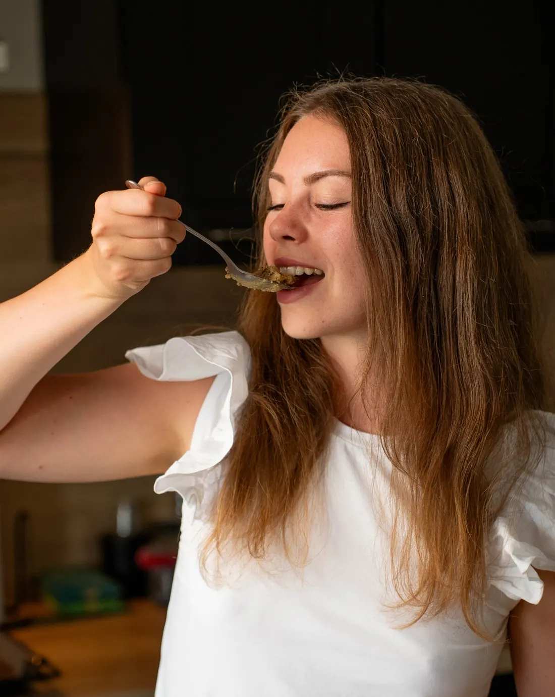 Adèle qui goûte un plat dans sa cuisine
